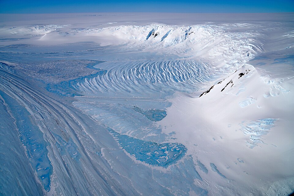 An image of blue ice in the Transantarctic Mountains. The light blue patches are wind-eroded blue ice, with the dark blue areas being formed by refreezing of meltwater (from https://commons.wikimedia.org/wiki/File:Transantarctic_pho_2017334_lrg.jpg).